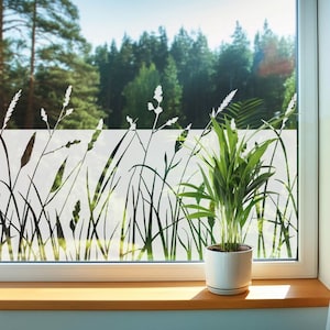 Puede incluir: Una ventana con una película de vidrio esmerilado blanco que presenta una silueta de hierba alta y flores. Una planta verde en maceta se encuentra en el alféizar de la ventana.