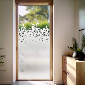 Peut inclure: Une porte en verre givré avec un autocollant en vinyle blanc de branches feuillues. L'autocollant est placé en haut de la porte, couvrant le tiers supérieur du verre.