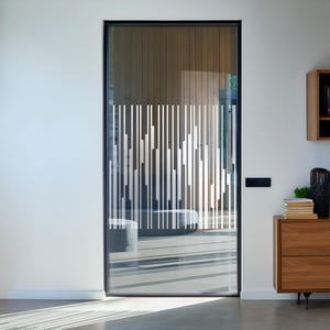 Può includere: Una porta in vetro moderna con cornice nera e un motivo geometrico bianco. La porta è aperta e rivela una stanza con pavimento in legno e una parete in legno.