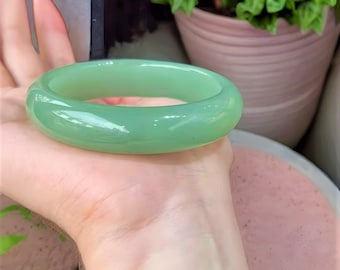 May include: A smooth, green jade bangle bracelet. The bracelet is round and has a polished finish.