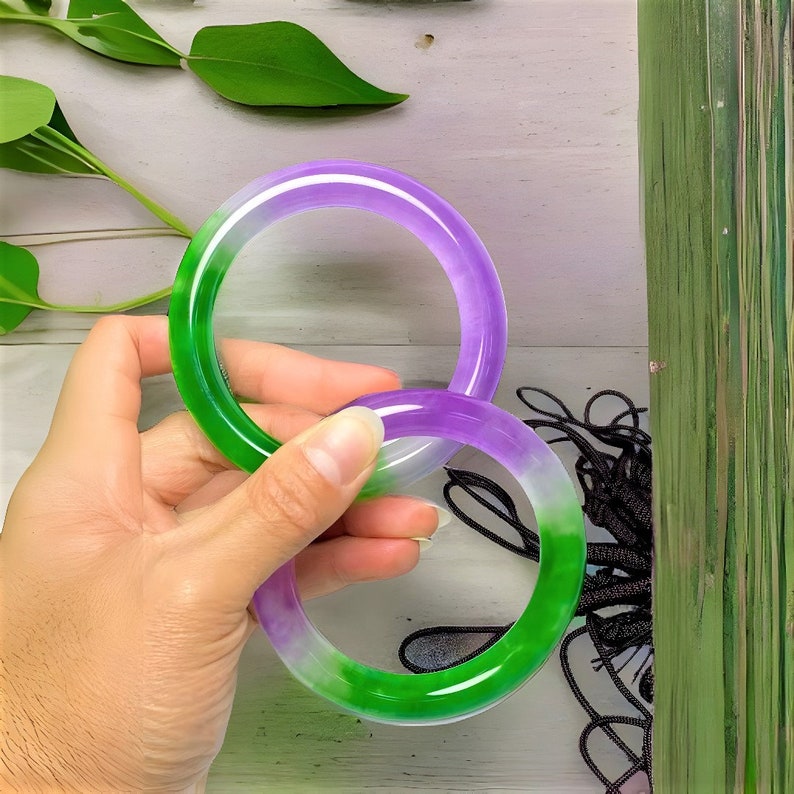 May include: Two jade bangles, one green and one purple, with a gradient color effect. The bangles are stacked on top of each other.