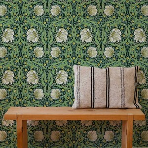 May include: A wooden bench with a white and black striped pillow sits in front of a green wallpaper with a floral pattern. The wallpaper features white flowers, green leaves, and yellow accents.