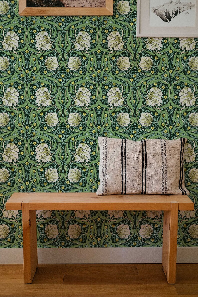May include: A wooden bench with a white and black striped pillow sits in front of a green wallpaper with a floral pattern. The wallpaper features white flowers, green leaves, and yellow accents.