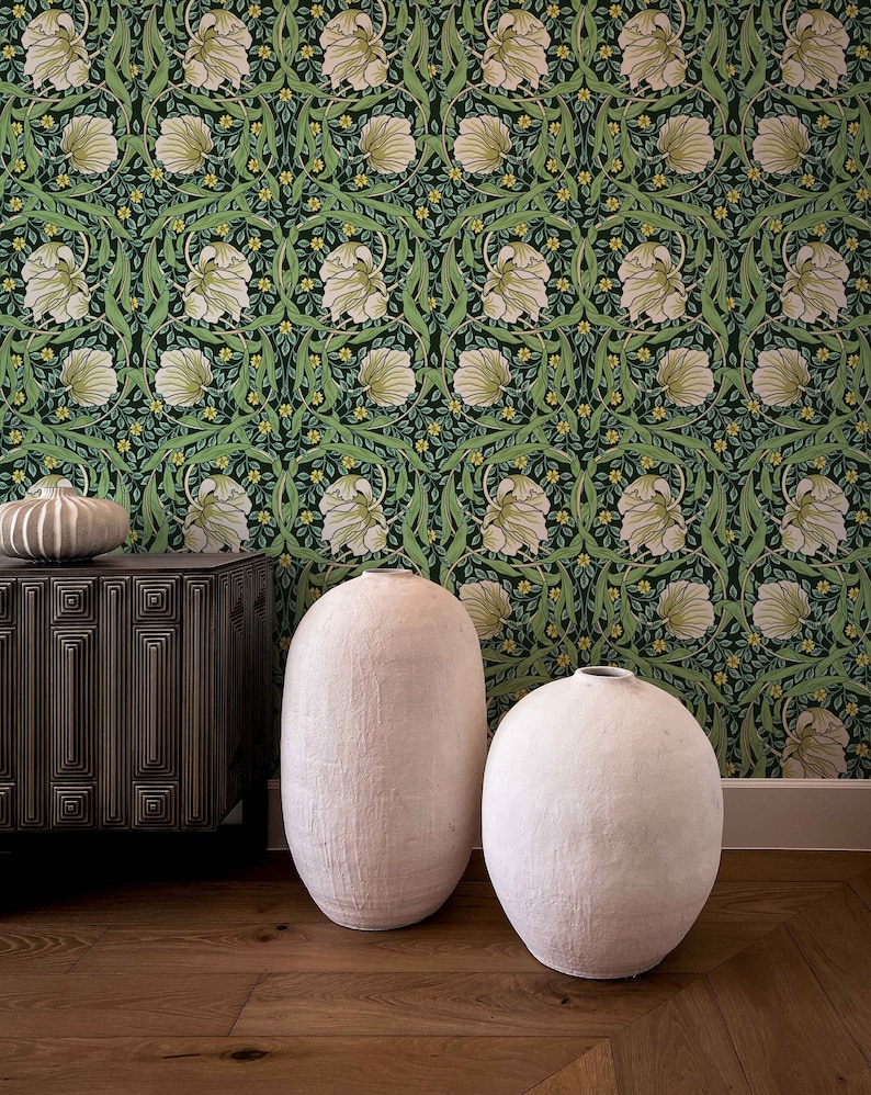 May include: Two white ceramic vases with a textured surface, sitting on a wooden floor in front of a green and white floral wallpaper.