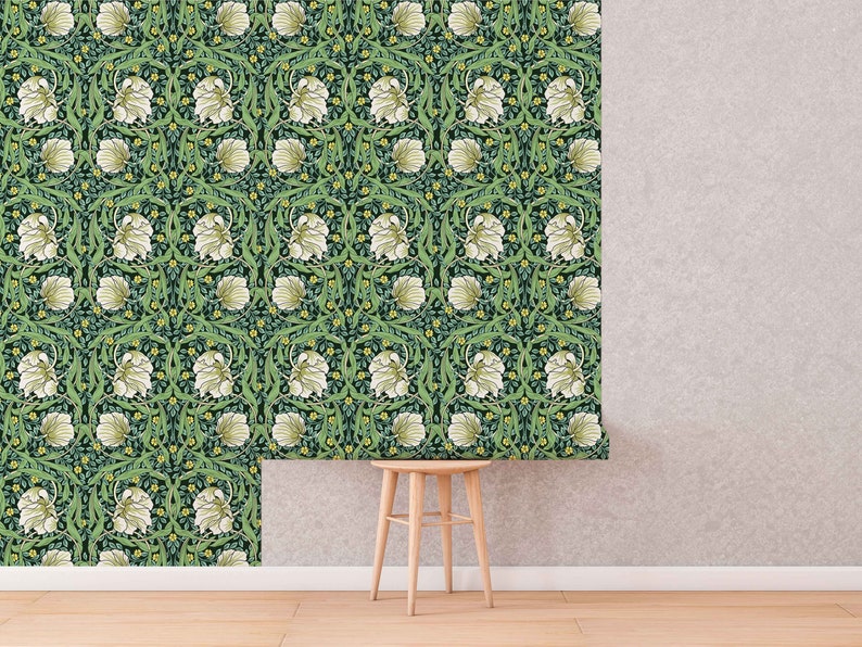 May include: A green and white floral wallpaper pattern with a repeating design of white flowers and green leaves. The wallpaper is shown on a wall with a wooden stool in front of it.