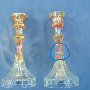 May include: A pair of iridescent glass candle holders with a textured design. The candle holders are clear with a slight amber hue. The candle holders are in a vintage style.