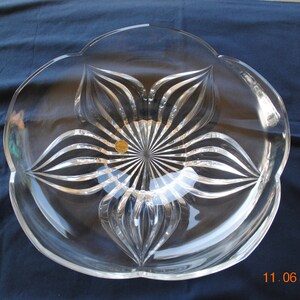 May include: A clear glass serving bowl with a flower-shaped design. The bowl has a scalloped edge and a raised center with a starburst pattern.