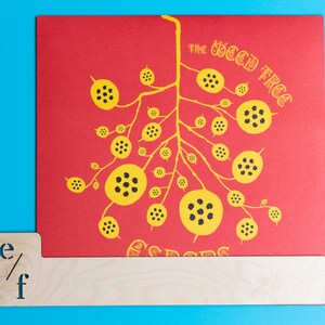 Puede incluir: Una tarjeta roja con una ilustraci&oacute;n en negro y amarillo de un &aacute;rbol con el texto "The Weed Tree Seeds" impreso en ella.