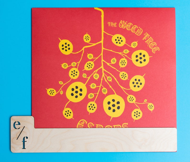 Puede incluir: Una tarjeta roja con una ilustraci&oacute;n en negro y amarillo de un &aacute;rbol con el texto "The Weed Tree Seeds" impreso en ella.