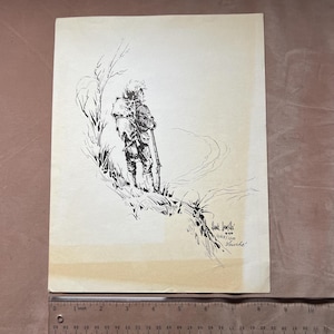 May include: A black and white ink illustration on off-white paper depicting a person in outdoor gear carrying a rifle and a pack, standing on a grassy slope. A clear plastic ruler at the bottom shows the print is approximately 8.5 inches wide.
