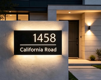 Könnte beinhalten: Ein rechteckiges, schwarzes Hausnummernschild mit Hintergrundbeleuchtung. Das Schild zeigt die Zahl 1458 in einer großen serifenlosen Schrift über einer horizontalen Linie, mit dem Text California Road in kleinerer Schrift darunter.
