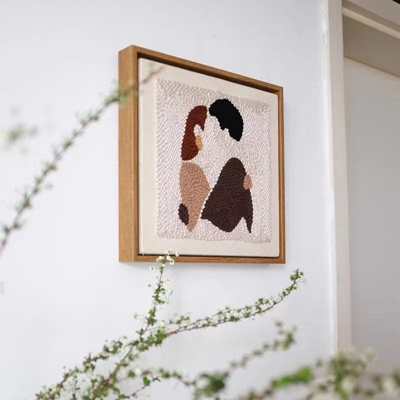Puede incluir: Una pieza de arte abstracto enmarcada con un fondo blanco y dos figuras en marr&oacute;n, beige y negro. Las figuras est&aacute;n en una pose de abrazo.