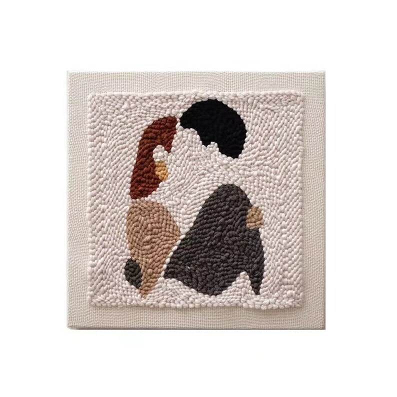 Puede incluir: Un tapiz de pared de lona beige con un dise&ntilde;o cosido a mano de dos figuras abstractas en marr&oacute;n, beige y negro.