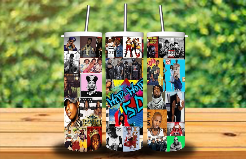 May include: Three white tumblers with lids and straws feature a collage of hip hop artists and album covers from the 1990s. The tumblers are on a wooden surface with a green background.