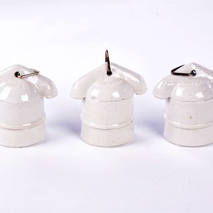 May include: Three off-white ceramic light bulb sockets with a flower-like top and a metal loop. The sockets are arranged in a row against a white background. The text "HUBBELL" is visible on the top of the sockets.