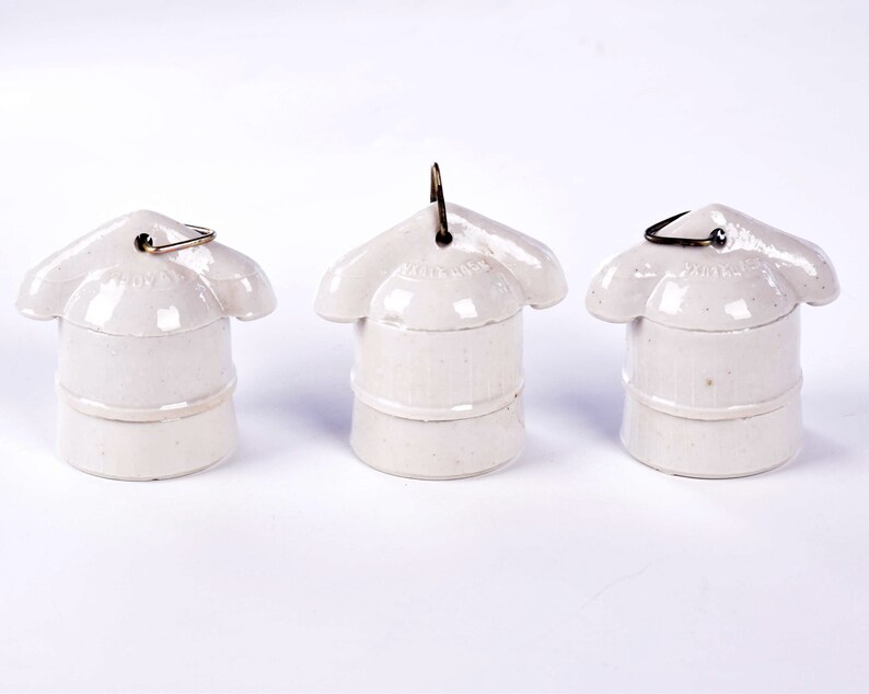 May include: Three off-white ceramic light bulb sockets with a flower-like top and a metal loop. The sockets are arranged in a row against a white background. The text "HUBBELL" is visible on the top of the sockets.