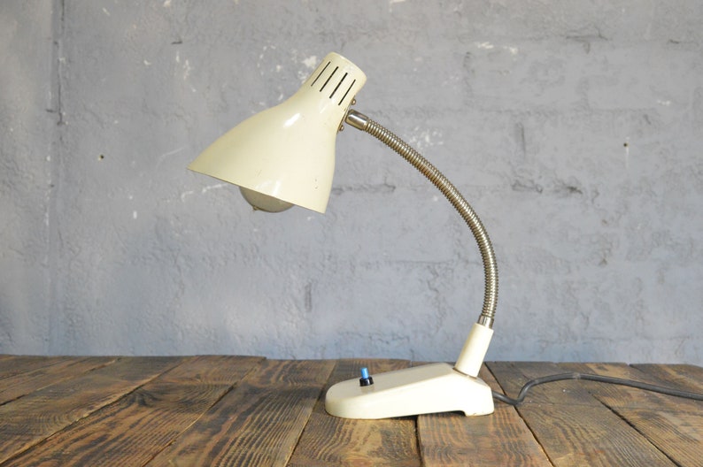 K&ouml;nnte beinhalten: Eine wei&szlig;e Vintage-Tischlampe mit flexiblem Arm und wei&szlig;em Schirm. Die Lampe hat einen einfachen Ein-/Ausschalter.