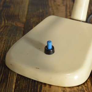 K&ouml;nnte beinhalten: Eine wei&szlig;e Schreibtischlampe mit einem schwarzen und blauen Schalter.