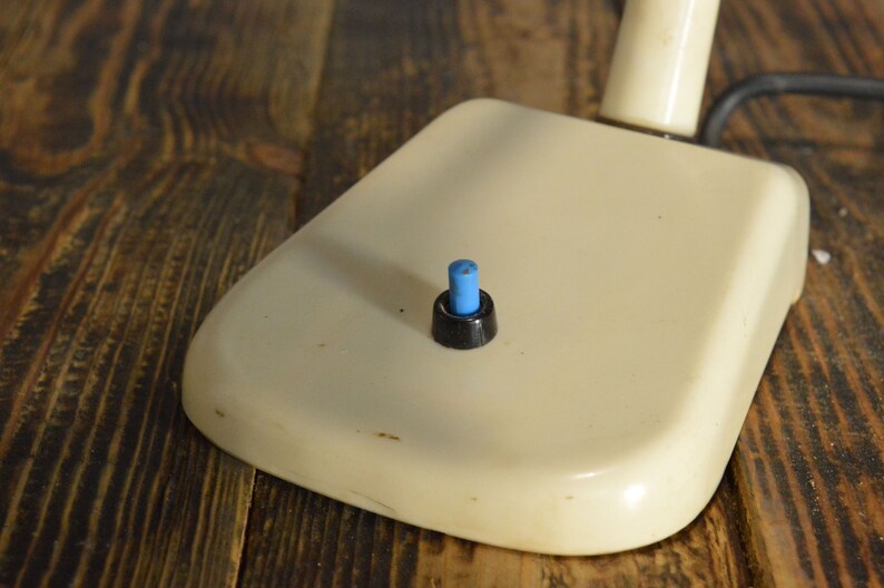 K&ouml;nnte beinhalten: Eine wei&szlig;e Schreibtischlampe mit einem schwarzen und blauen Schalter.
