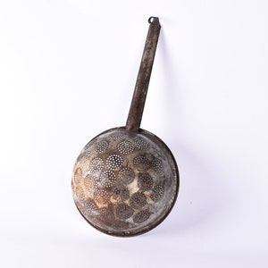May include: A vintage metal strainer with a long handle and a round, perforated bowl. The strainer is rusty and has a worn, aged appearance.
