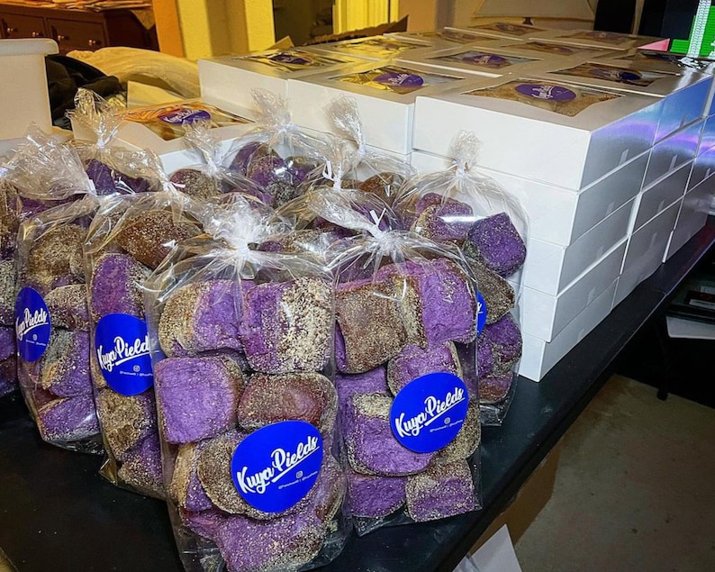 May include: A close-up of several bags filled with purple and brown ube bread. The bags are labeled "Kuya Piele's" and are stacked on a table. The bread is a popular Filipino dessert.