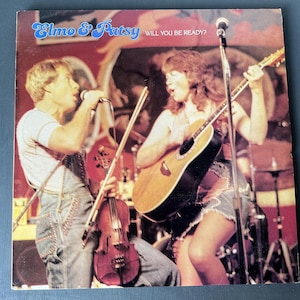 May include: A vintage record album cover featuring a man and a woman performing on stage. The man is playing a violin and the woman is playing a guitar. The album cover is titled "Elmo & Patsy" and the text "Will You Be Ready?" is printed below the title.