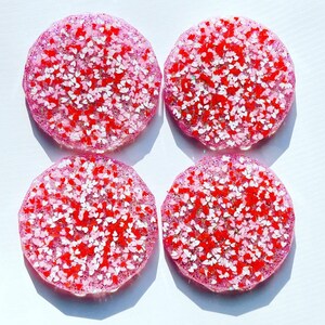 May include: Four pink and white resin coasters with a heart-shaped glitter design.