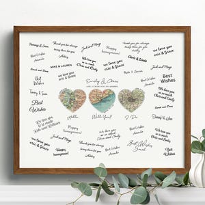May include: A framed print featuring three heart-shaped map designs in shades of brown, blue, and green. The print includes handwritten messages and the names "Emily & Chris". The frame is a warm brown color.