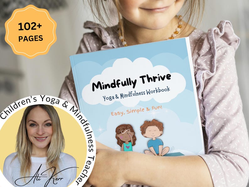 K&ouml;nnte beinhalten: Ein junges M&auml;dchen h&auml;lt ein blaues und wei&szlig;es Buch mit dem Titel "Mindfully Thrive: Yoga & Mindfulness Workbook". Der Buchumschlag zeigt eine Comic-Illustration von zwei Kindern, die Yoga-Posen einnehmen. Das Buch wird als "Einfach, Einfach & Spa&szlig;!" beschrieben und hat &uuml;ber 102 Seiten.