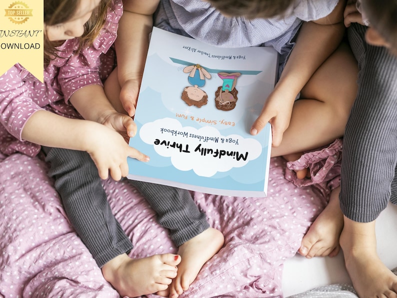 K&ouml;nnte beinhalten: Zwei Kinder sitzen auf einer rosa Decke und betrachten ein Buch mit dem Titel "Mindfully Thrive: Yoga & Mindfulness Workbook, Easy, Simple & Fun".