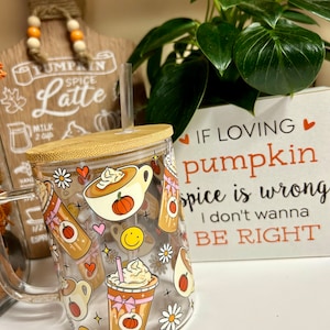 May include: A clear glass mug with a bamboo lid and a straw. The mug has a fall-themed design with pumpkins, coffee cups, and flowers. The text on the mug reads "If loving pumpkin spice is wrong, I don't wanna be right."