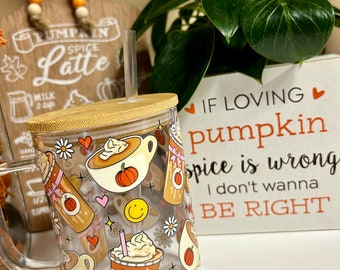May include: A clear glass mug with a bamboo lid and a straw. The mug has a fall-themed design with pumpkins, coffee cups, and flowers. The text on the mug reads "If loving pumpkin spice is wrong, I don't wanna be right."