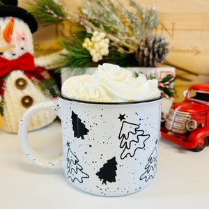 May include: White ceramic mug with black and white Christmas tree designs and black speckles. The mug is filled with a white whipped cream topping.