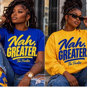 May include: A royal blue short-sleeve t-shirt and a mustard yellow long-sleeve sweatshirt, both featuring the text "Nah, GREATER. The Poodles" printed in a bold, brush-stroke style font. The t-shirt has yellow text, while the sweatshirt has blue text.