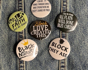 Pode incluir: Seis botões redondos com diferentes mensagens e designs. Os botões estão sobre um fundo de denim azul. Os botões apresentam o seguinte texto: "Walk by Faith, Not by Sight", "I can do all things through Christ who strengthens me except change my price", "Black Love Created This", "Black by Nature", "I Like My Wings All Flats Well Done Bleu Cheese", e "Block They Ass".