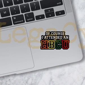 May include: A sticker with the text "OF COURSE I ATTENDED AN HBCU" in black, red, yellow, and green letters on a silver laptop.