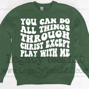 May include: Green sweatshirt with white text that reads "You can do all things through Christ except play with me". The text is in a retro font style. The sweatshirt also has the text "Legacy Tees LLC" and "www.LegacyTeesLLC.com" in black.