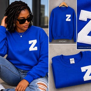 Puede incluir: Una sudadera azul real de cuello redondo con una letra Z blanca grande en el pecho izquierdo. La letra es un parche de chenilla texturizado. La prenda tiene mangas largas, un cuello acanalado y una etiqueta de la marca Gildan en el interior.