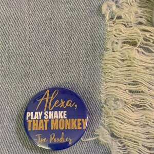 May include: A blue button with gold text that reads "Alexa, Play Shake That Monkey - The Poodles".