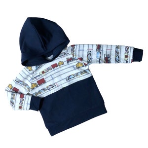 May include: A navy blue hooded sweatshirt with a white and blue train pattern on the top half. The bottom half of the sweatshirt is solid navy blue.