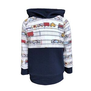 May include: A white and navy blue hooded sweatshirt with a train pattern on the top half. The train pattern features a variety of train cars, including boxcars, tank cars, and locomotives. The sweatshirt has a kangaroo pocket and long sleeves.