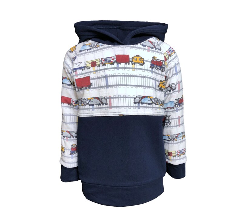 May include: A white and navy blue hooded sweatshirt with a train pattern on the top half. The train pattern features a variety of train cars, including boxcars, tank cars, and locomotives. The sweatshirt has a kangaroo pocket and long sleeves.