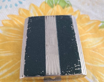 May include: A vintage silver and green compact with a decorative design. The compact has a hinged lid and a small mirror inside.