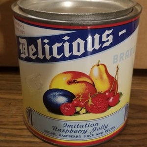 May include: A vintage can of Delicious Brand Imitation Raspberry Jelly. The can is red, yellow, and blue with a picture of fruit on the front. The text on the can reads "Delicious Brand Imitation Raspberry Jelly Sugar, Raspberry Juice and Pectin".