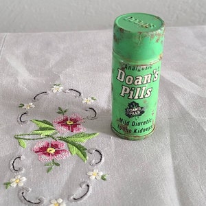 May include: A vintage green metal tin of Doan's Pills, an analgesic and mild diuretic for the kidneys. The tin has a white label with the brand name and product description.