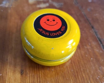 Vintage Yellow Metal Yo-Yo with Jesus Loves You sticker in the center on both sides.