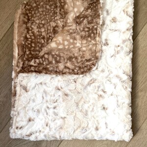 May include: A soft, plush throw blanket with a brown and white spotted pattern on one side and a white, fluffy texture on the other side.