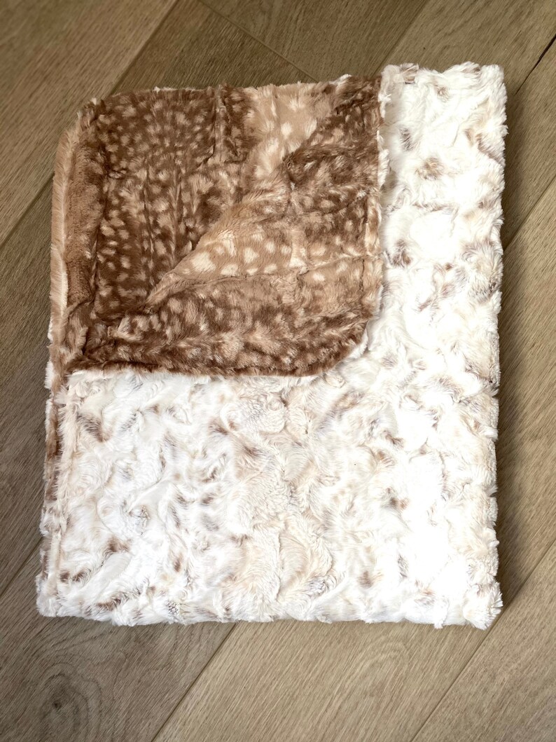 May include: A soft, plush throw blanket with a brown and white spotted pattern on one side and a white, fluffy texture on the other side.