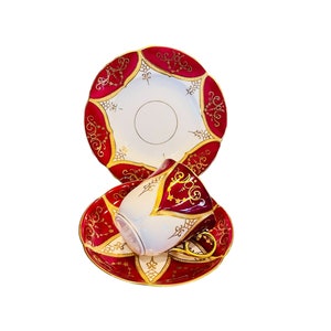 Könnte beinhalten: Ein Set aus roten und goldenen Teetassen und Untertassen mit aufwendigen Blumendesigns. Die Tassen und Untertassen sind aus Porzellan und haben ein weißes Inneres.