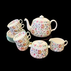 May include: A vintage floral tea set comprising a teapot, creamer, sugar bowl, and four cups and saucers. The set features a delicate floral pattern in shades of pink, yellow, and green.